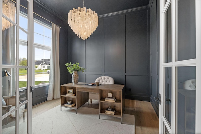 home office with ornamental molding, a notable chandelier, wood finished floors, and a decorative wall