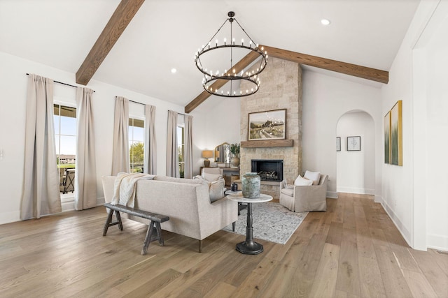 living room with light wood finished floors, an inviting chandelier, beam ceiling, baseboards, and arched walkways