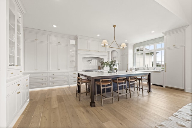 interior space featuring a chandelier, white cabinets, glass insert cabinets, and light countertops