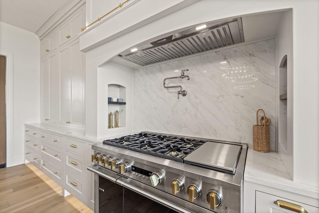kitchen featuring light stone counters, arched walkways, high end stainless steel range, and white cabinetry