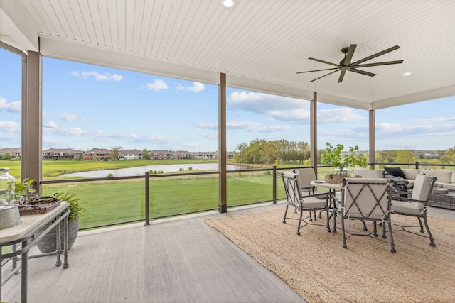 sunroom featuring a ceiling fan, a water view, and expansive windows