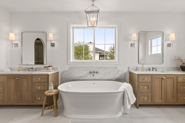 bathroom with a freestanding tub, two vanities, and a sink