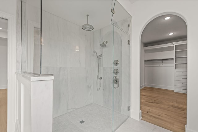 full bath with recessed lighting, wood finished floors, a shower with shower door, baseboards, and a spacious closet