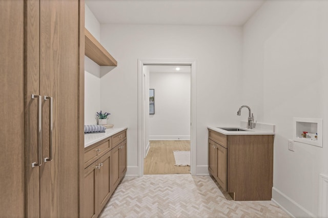 laundry area with cabinet space, a sink, washer hookup, baseboards, and parquet floors