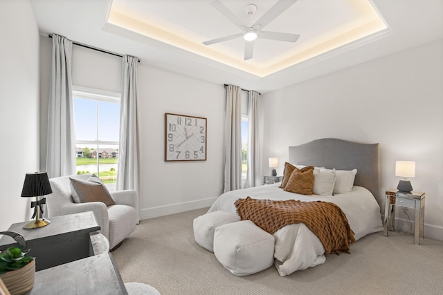bedroom featuring baseboards, ceiling fan, carpet flooring, and a tray ceiling