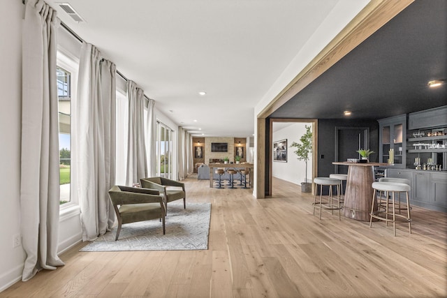 interior space featuring visible vents, light wood-type flooring, indoor wet bar, and plenty of natural light