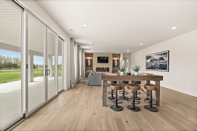 dining room featuring recessed lighting, a stone fireplace, and light wood-style flooring