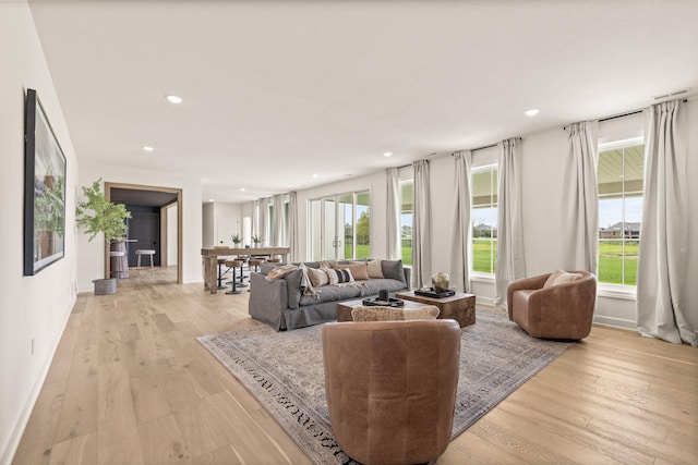 living area featuring recessed lighting, baseboards, light wood-style floors, and a healthy amount of sunlight