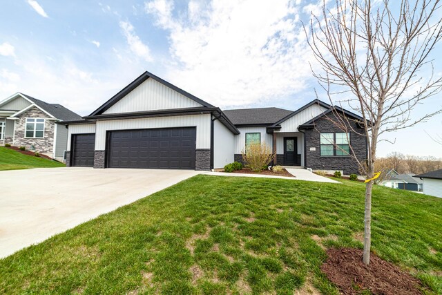 view of front of home with a garage, a front yard, concrete driveway, and stone siding