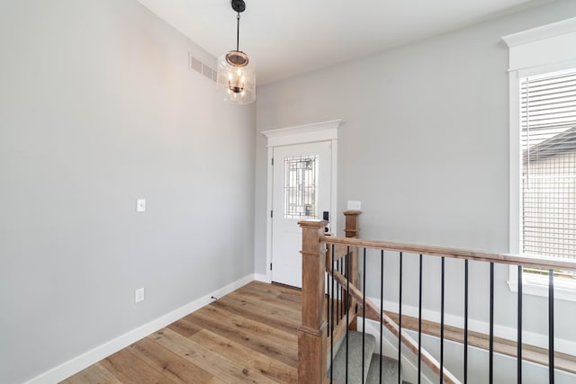 interior space with an upstairs landing, visible vents, light wood-type flooring, and baseboards