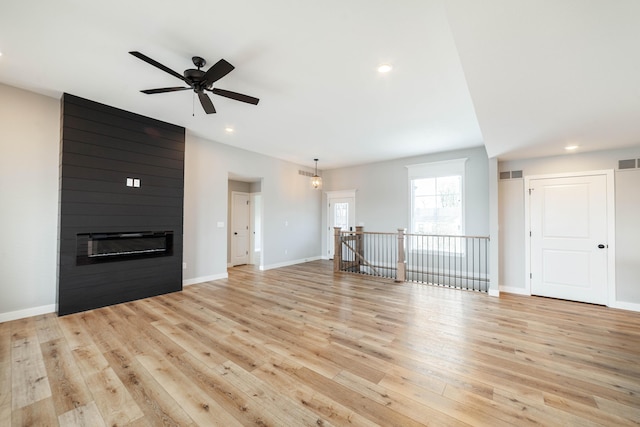 unfurnished living room featuring visible vents, a ceiling fan, light wood-style floors, and a fireplace