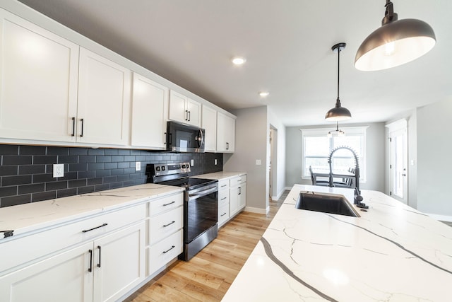 kitchen featuring light wood finished floors, a sink, stainless steel range with electric cooktop, black microwave, and backsplash