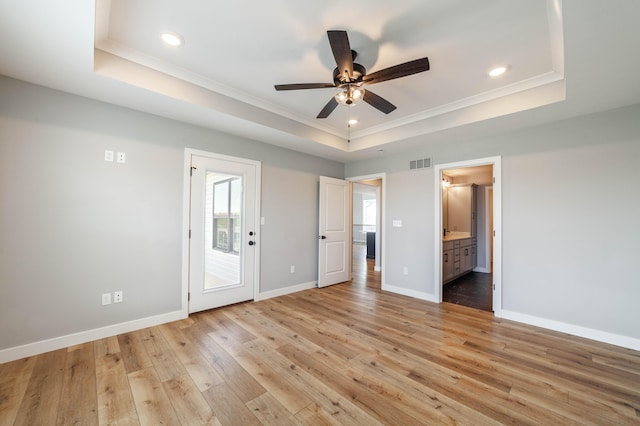 unfurnished bedroom featuring visible vents, a raised ceiling, baseboards, light wood-type flooring, and ornamental molding