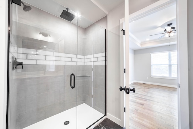 full bathroom with a ceiling fan, a shower stall, and baseboards