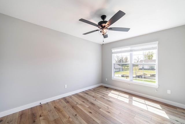 spare room featuring baseboards, visible vents, ceiling fan, and light wood-style floors
