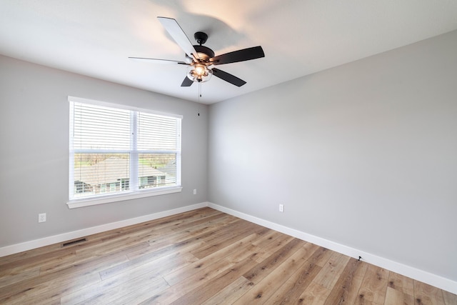 empty room featuring baseboards, visible vents, a ceiling fan, and light wood finished floors