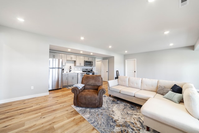 living room featuring baseboards, visible vents, light wood-style floors, and recessed lighting