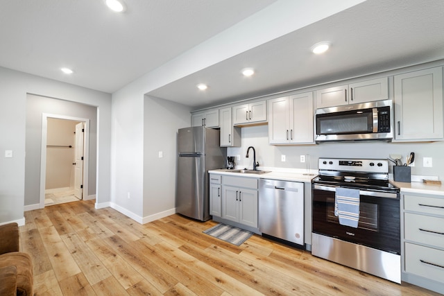 kitchen with light countertops, a sink, appliances with stainless steel finishes, and gray cabinets