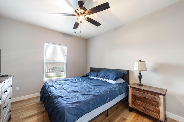 bedroom with baseboards, visible vents, a ceiling fan, and light wood-style flooring