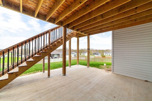 view of patio featuring fence, stairway, and a residential view