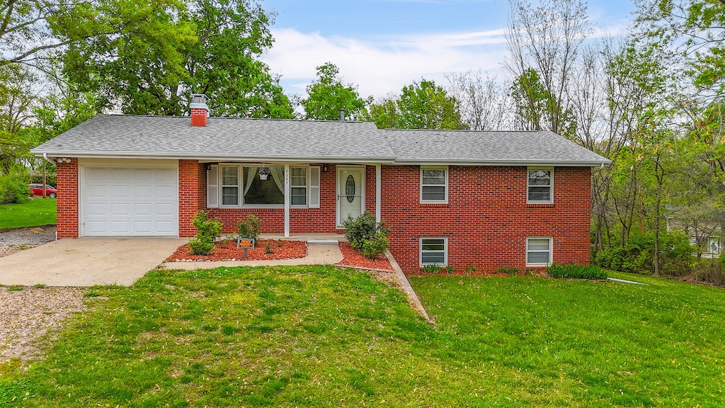 single story home with a front yard, brick siding, driveway, a chimney, and an attached garage