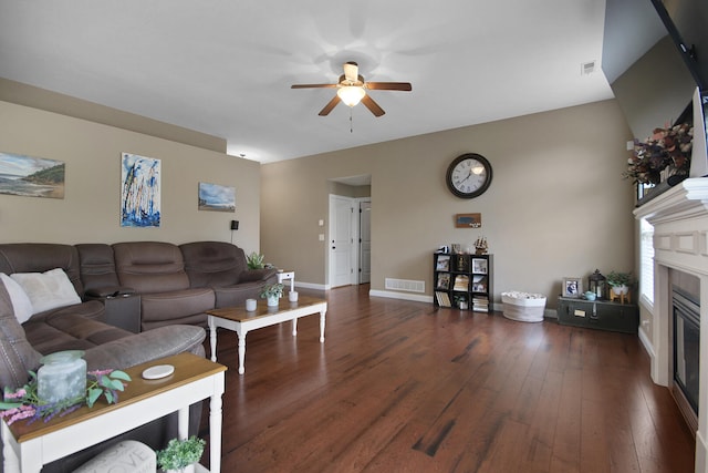 living area featuring a glass covered fireplace, visible vents, a ceiling fan, and wood-type flooring