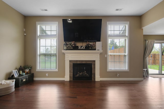 living room with a tile fireplace, visible vents, wood finished floors, and baseboards