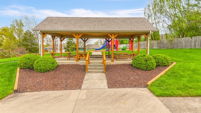 view of community featuring fence, playground community, a gazebo, and a yard