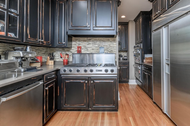 403 Westmount Ave, Columbia, MO 65203 - kitchen with stainless steel appliances, light wood-type flooring, tasteful backsplash, recessed lighting, and glass insert cabinets