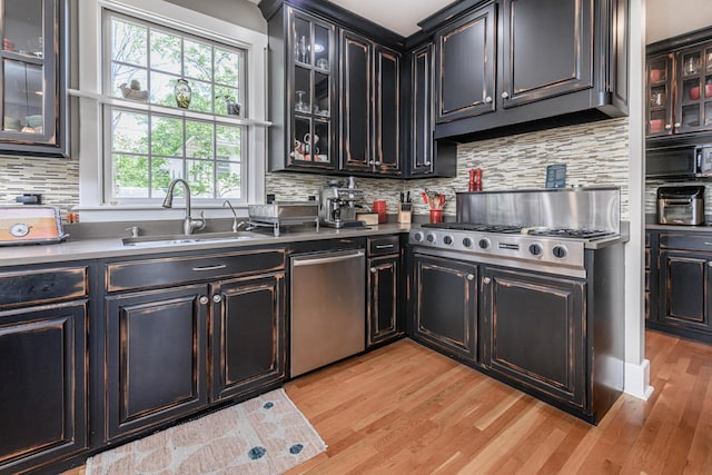 403 Westmount Ave, Columbia, MO 65203 - kitchen featuring stainless steel appliances, a sink, light wood-style floors, backsplash, and glass insert cabinets