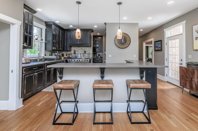 403 Westmount Ave, Columbia, MO 65203 - kitchen with light wood-type flooring, a breakfast bar area, decorative backsplash, glass insert cabinets, and recessed lighting