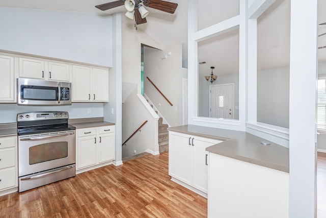 4983 N Montgomery Dr, Columbia, MO 65202 - kitchen with stainless steel appliances, white cabinets, a ceiling fan, light wood-style floors, and high vaulted ceiling