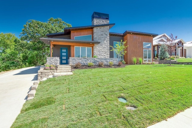 contemporary house with stone siding, a front lawn, and a chimney
