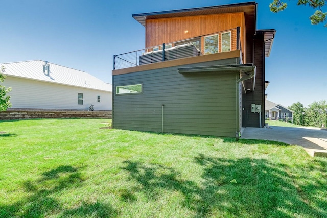 back of house with a balcony and a lawn