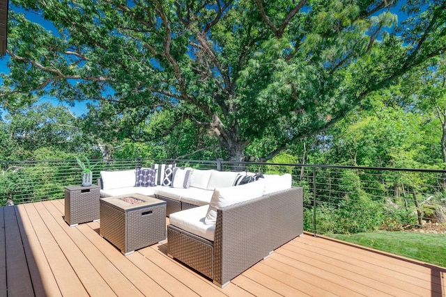 deck with an outdoor living space with a fire pit and view of wooded area