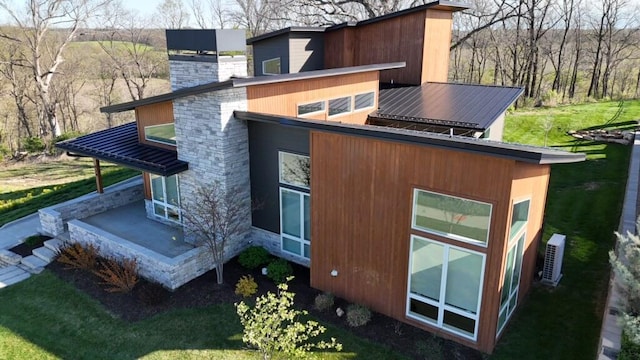 view of side of property with a chimney, stone siding, and metal roof