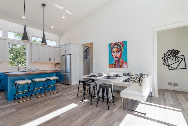 dining area with light wood-type flooring, high vaulted ceiling, recessed lighting, and baseboards