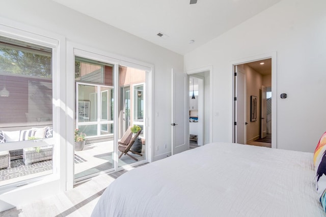 bedroom with access to outside, multiple windows, vaulted ceiling, and wood finished floors