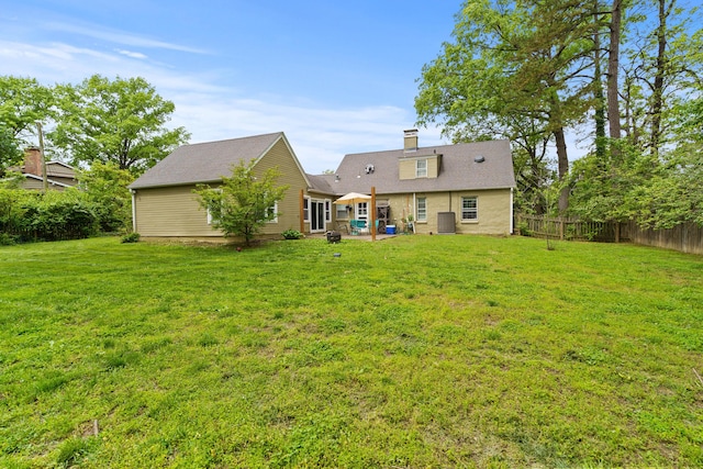 rear view of property with fence, a patio, a chimney, and a lawn