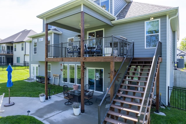 rear view of house featuring roof with shingles, fence, a yard, a patio, and stairs
