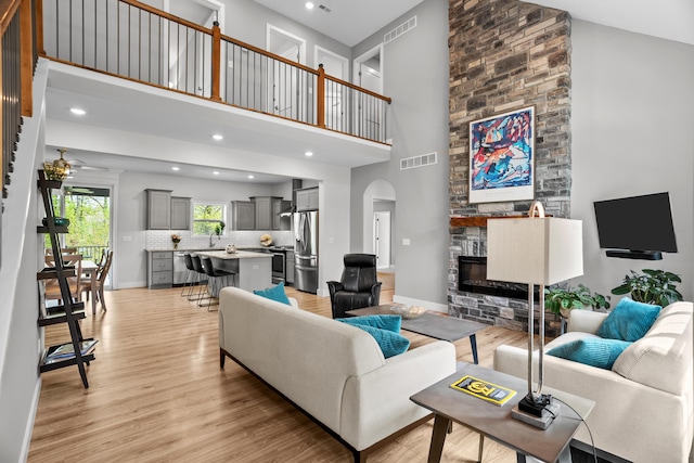 living area featuring arched walkways, a high ceiling, a fireplace, and visible vents