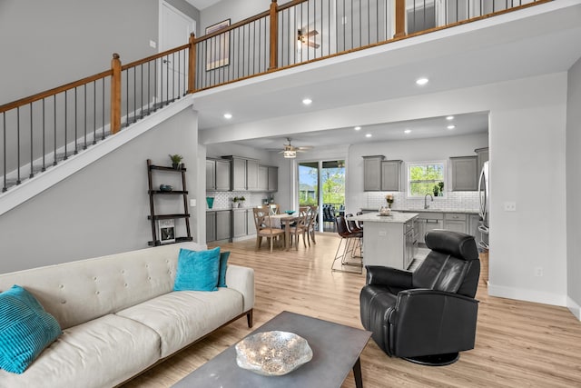 living room with light wood-style floors, stairs, a ceiling fan, baseboards, and recessed lighting