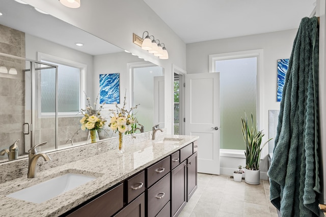 full bath with double vanity, tile patterned floors, a sink, and a stall shower