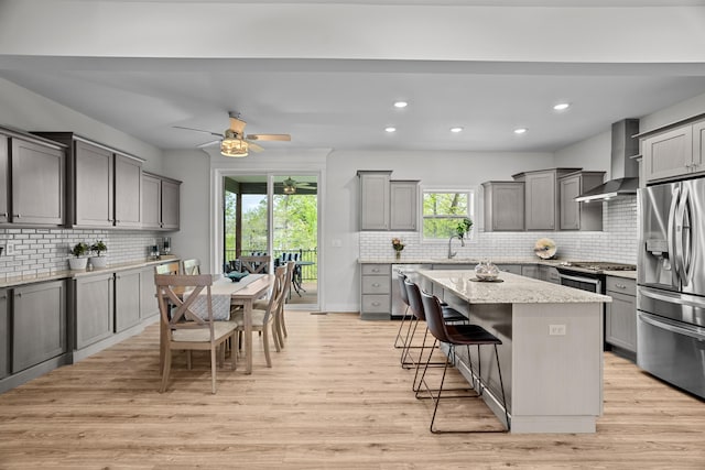 kitchen featuring stainless steel appliances, decorative backsplash, gray cabinets, and wall chimney exhaust hood
