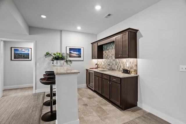 bar featuring a sink, beverage cooler, baseboards, decorative backsplash, and visible vents