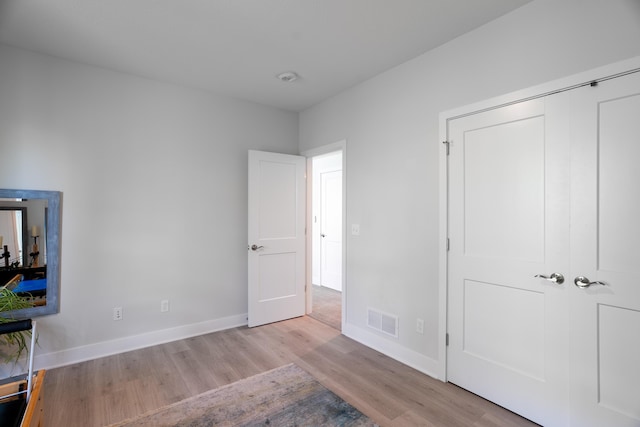 unfurnished bedroom featuring baseboards, visible vents, and wood finished floors