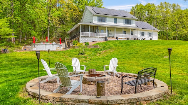 7751 W Old Barclay Creek Ln, Columbia, MO 65202 - back of property featuring a fire pit, roof mounted solar panels, a sunroom, and a yard