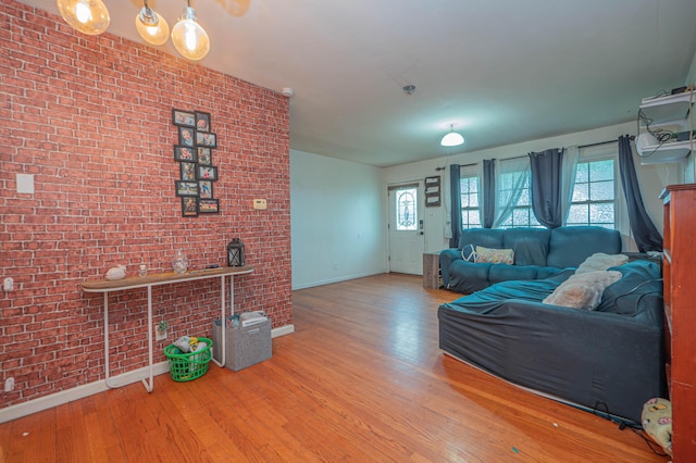 living room with baseboards, brick wall, and hardwood / wood-style flooring