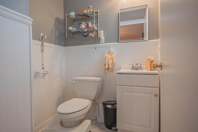 bathroom featuring toilet, a wainscoted wall, and vanity