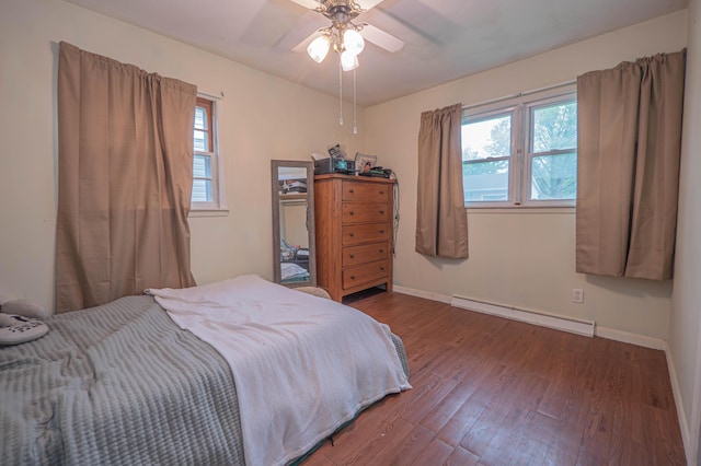 bedroom with wood finished floors, a ceiling fan, baseboards, and a baseboard heating unit